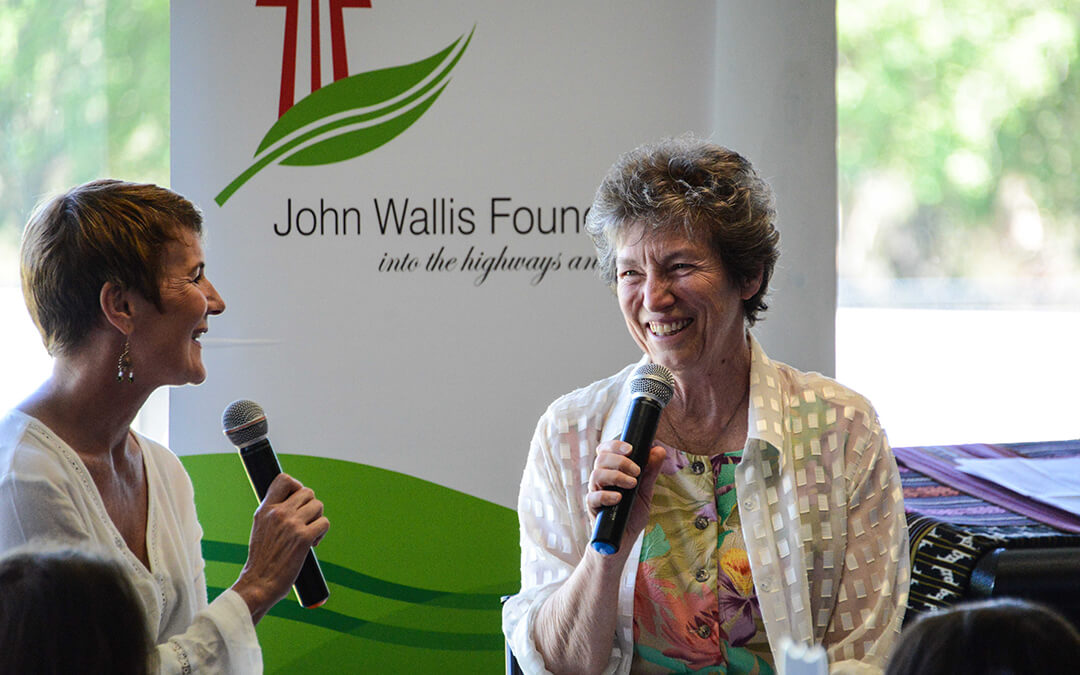 Two women holding microphones speaking to each other.