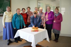 Group of women standing behind cake