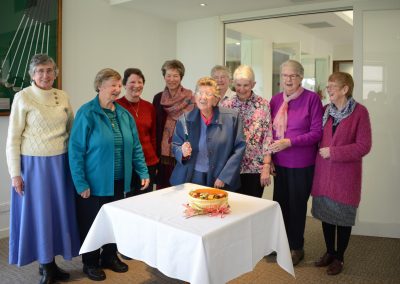 Women standing behind cake