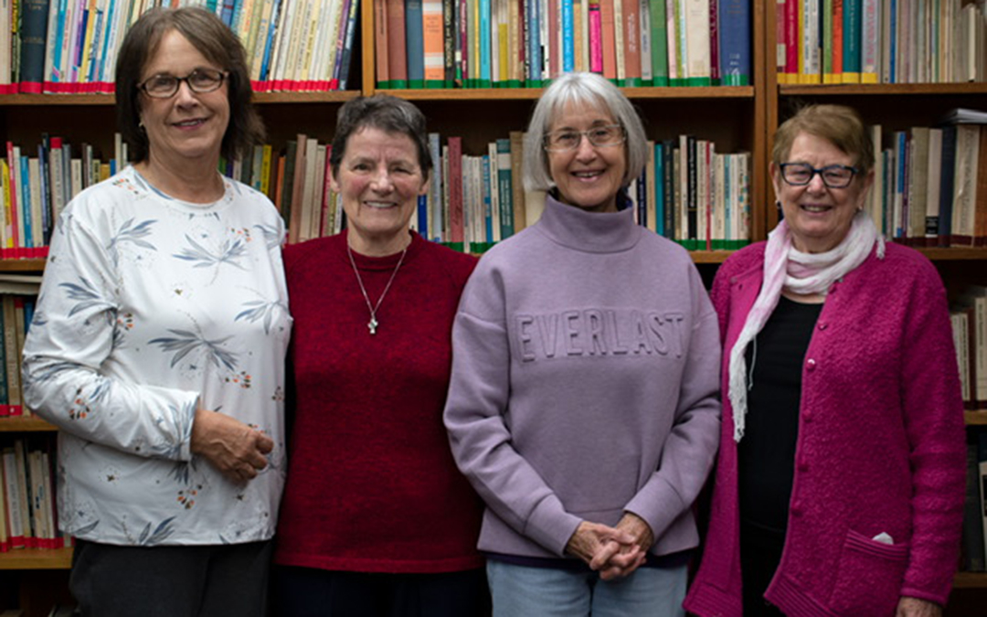Four women standing in a library