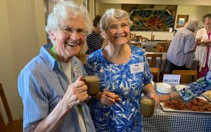 Two elderly women holding cups of tea