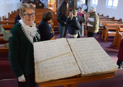 Bernadette Wallis standing in front of Baptism Registry book