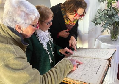 Three women looking over Baptism Registry
