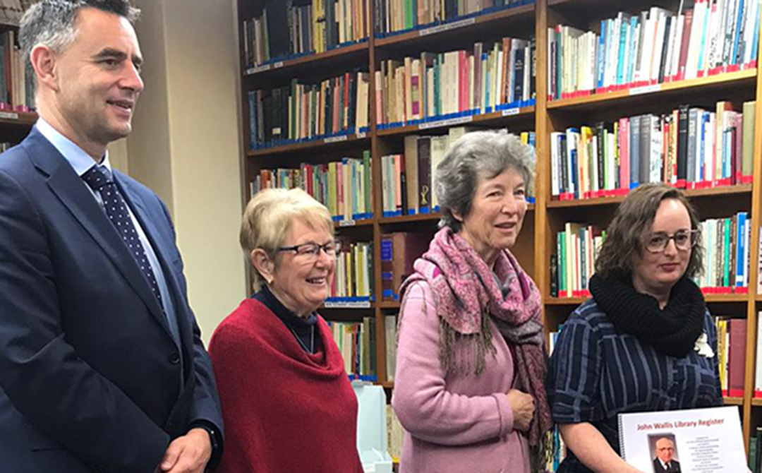 Four people standing in a row in a library