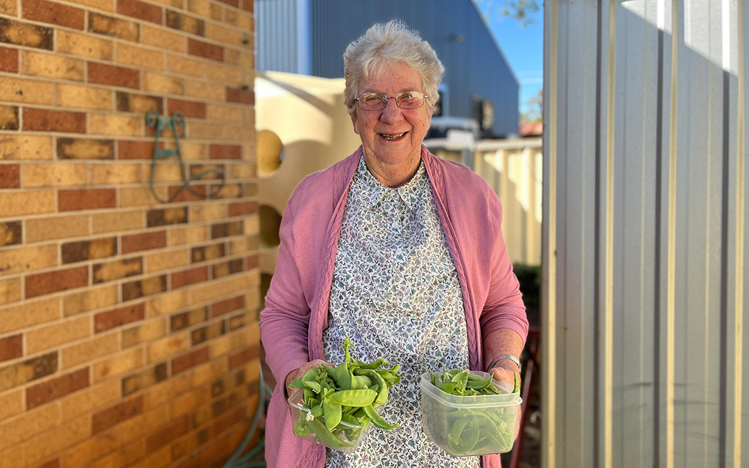 Woman in yard holding vegetables