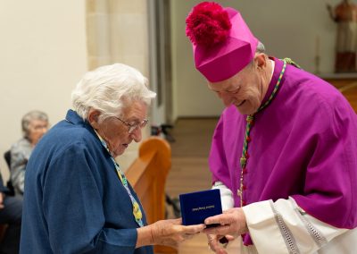 Older woman receiving medal from Archbishop