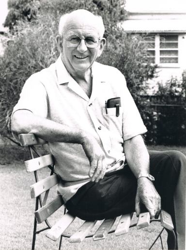 Older man sitting on park bench in black and white Fr John Wallis